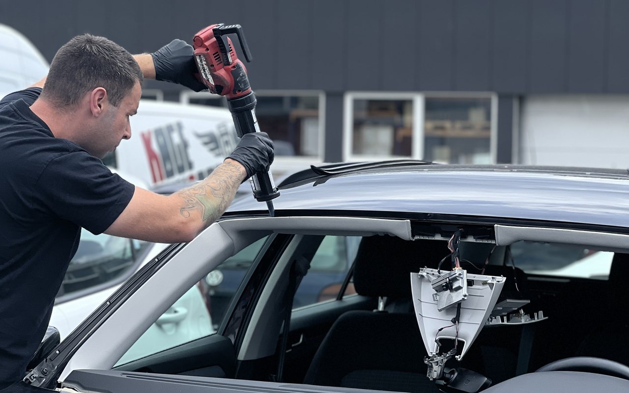 Autoglasmontør skærer en forrude ud